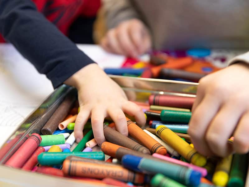 Childrens hands grabbing coloured pencils